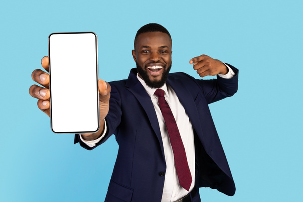 Komea musta liikemies puvussa osoittaa Big Blank älypuhelin kädessä - Valokuva, kuva