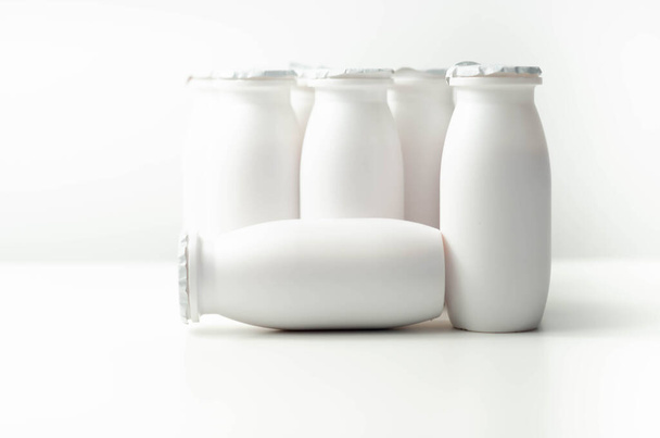Bílé plastové jogurtové láhve na bílém pozadí, typický obal pro mléčné výrobky, produktová láhev - Fotografie, Obrázek