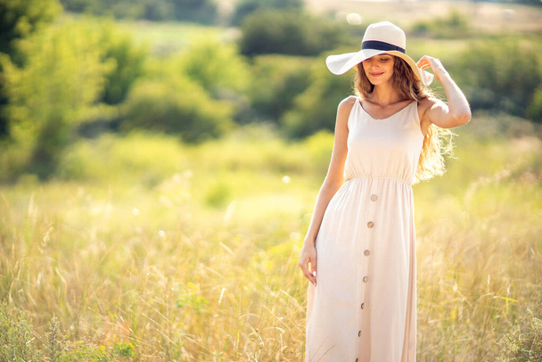 Güneş şapkalı ve açık havada poz veren romantik elbiseli güzel beyaz kız. Moda Yaşam Tarzı - Fotoğraf, Görsel