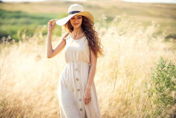 Beautiful adult caucasian girl in sunhat and romantic dress who walks outdoors. Fashion Lifestyle - Fotoğraf, Görsel