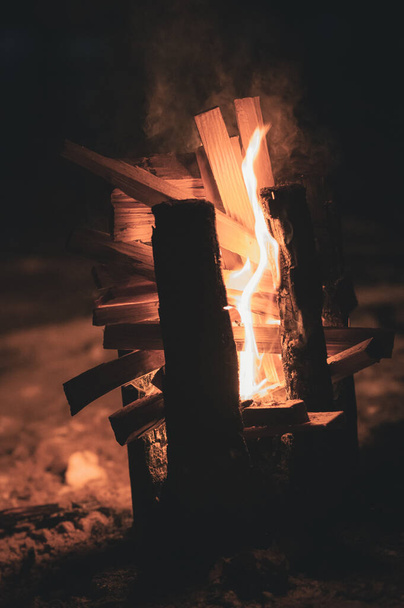 smoke from the flames of the fire and a wooden pole burning vertically from the grooves notched at the top, so that the fire better burns the wood from the inside like a torch - Photo, Image