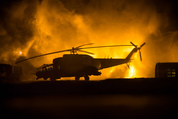 Silhouette eines Militärhubschraubers, der bereit ist, aus dem Konfliktgebiet zu fliegen. Dekorierte Nachtaufnahmen mit Helikoptern, die in der Wüste mit nebelgetöntem Gegenlicht starten. Selektiver Fokus. Kriegskonzept - Foto, Bild