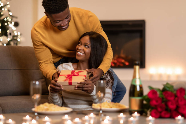 Black Husband Giving Valentine Gift To Wife During Dinner Indoor - 写真・画像