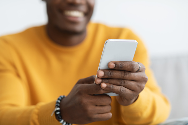 Αγνώριστος μαύρος που χρησιμοποιεί κινητό τηλέφωνο στο σπίτι - Φωτογραφία, εικόνα