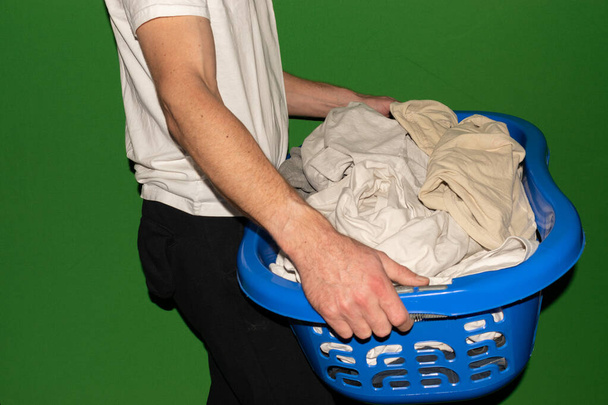 Vaduz, Liechtenstein, December 22, 2021 Person is carrying a basket full with soiled T-shirts - Foto, Bild