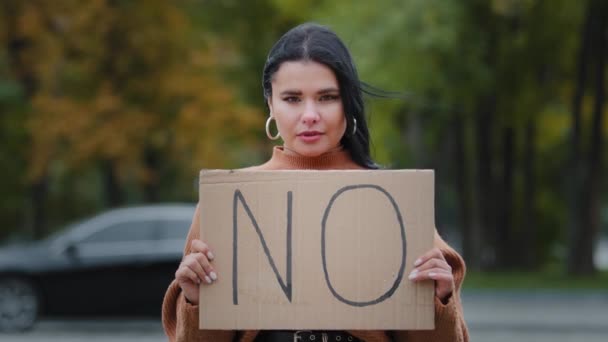 Lähikuva protesti tyttö seisoo ulkona katsomassa kameraa pitäen pahvi banneri NO yhteisön jäsen perheväkivaltaa vastaan rotusyrjintä taistelu naisten oikeuksien epääminen rokottaa - Materiaali, video