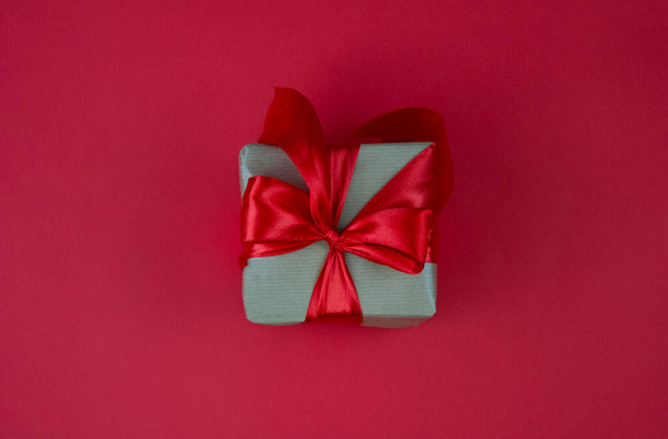 The concept of celebrating different holidays. Gift box with red bow on red background. Copy space. Celebrating Valentine's Day, Mother's Day, Christmas, Birthday. - Photo, image