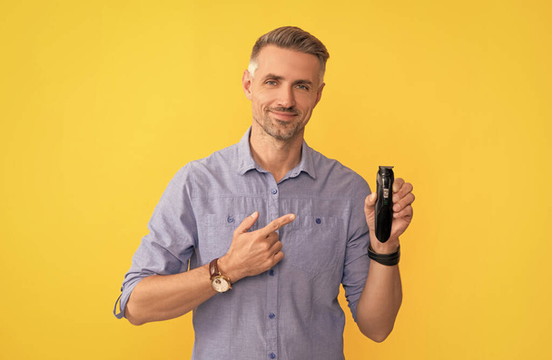 τύπος που δείχνει ηλεκτροφόρο ξυριστικό σε κίτρινο φόντο, ξυρισμένη - Φωτογραφία, εικόνα