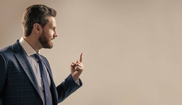 Professional man in suit sideway keep finger pointing up grey background copy space, idea - Photo, Image