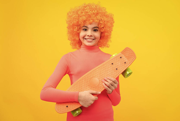 Happy girl scater con pelo naranja en rosa poloneck sonrisa celebración de pennyboard, monopatín - Foto, imagen