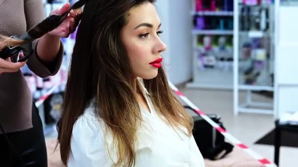 Kopf einer brünetten Frau mit gelocktem Haar zum Frisieren im Schönheitssalon. - Filmmaterial, Video