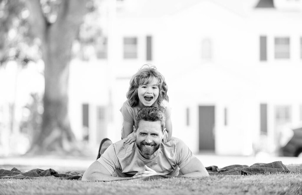 Щасливий син їздить батьки, розслабляючись на ковдрі, покладеному на траву влітку на відкритому повітрі, весело
 - Фото, зображення