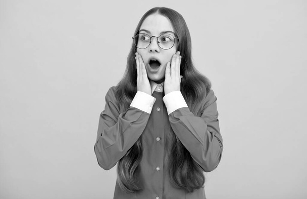 Σοκαρισμένο κορίτσι με γυαλιά σχολική εκπαίδευση κίτρινο φόντο, σοκ - Φωτογραφία, εικόνα