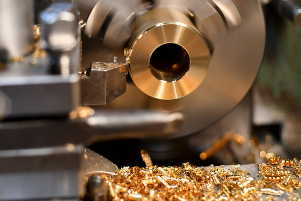 The bronze bushing is installed in the chuck jaws of the lathe and is processed with a mechanical cutter, removing the chips and bringing the part to the technological size. - Photo, Image