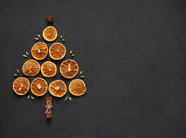 dried orange slices lay in the form of christmas tree on a board with cinnamon sticks, top view. copy space - Foto, Imagem