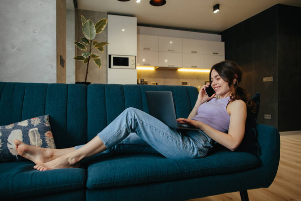 Girl uses laptop for remote work or home leisure while sitting in the kitchen at home. - Photo, image