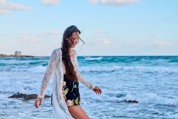 Beautiful young woman in a lace dress walking along the beach, copy space - Foto, Imagem