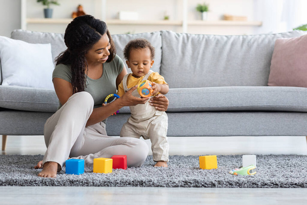 Caring Black Mom And Adorable Infant Son Playing With Toys At Home - Фото, зображення