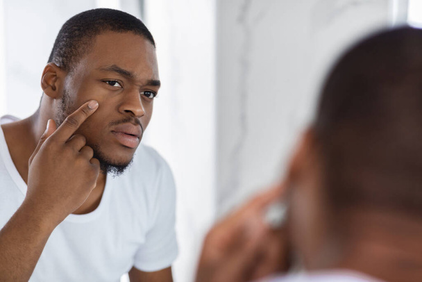 Concerned Black Young Man Examining His Face While Looking At Mirror - Foto, afbeelding