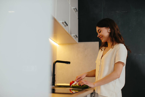 Young woman chopping vegetables in kitchen - stock photo - Valokuva, kuva