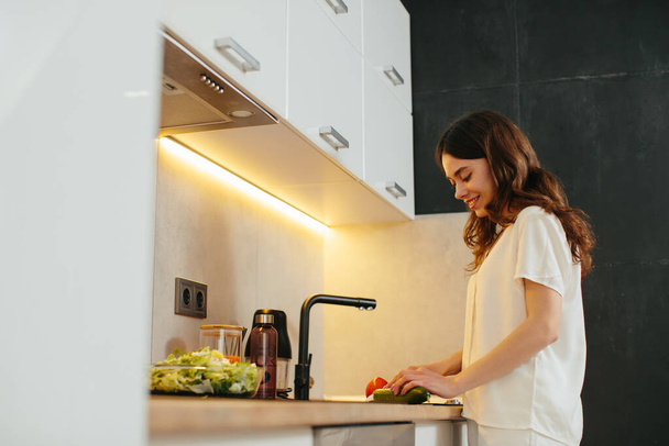 若い女性が台所で野菜を切る-株式写真 - 写真・画像