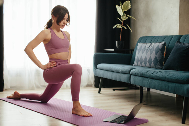Attraente giovane donna che fa yoga stretching yoga online a casa. L'autoisolamento è benefico, l'intrattenimento e l'educazione su Internet. Stile di vita sano concetto. - Foto, immagini