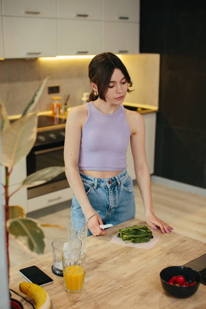 Giovane donna che prepara sano frullato verde in cucina - Foto, immagini