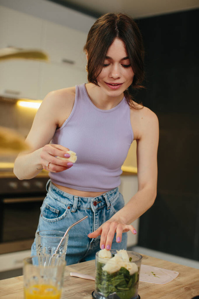 Молодая женщина готовит здоровый зеленый смузи на кухне - Фото, изображение