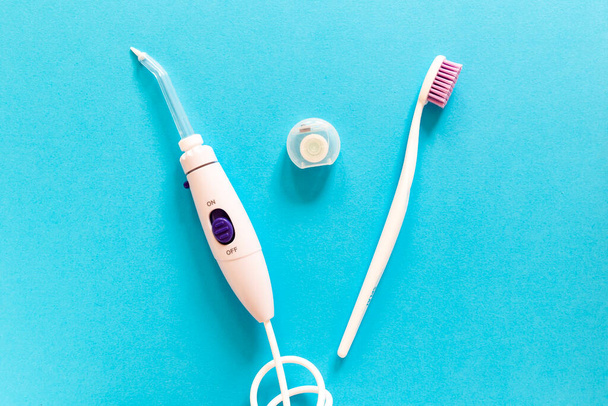 Flatlay of toothbrush, dental floss and irrigator on a blue background . Modern morning routine and oral mouth and teeth hygiene concept - Fotó, kép