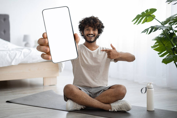 Happy indian guy showing smartphone with empty screen - Фото, изображение