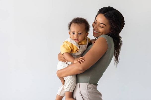 Μητέρα και παιδί. Ευτυχισμένη νεαρή Αφρο-Αμερικανίδα μαμά που κρατάει το μωρό της - Φωτογραφία, εικόνα