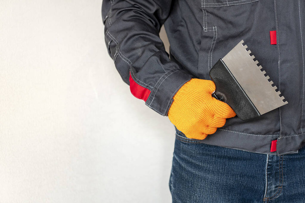  Spatule dans la main d'un travailleur. Des outils de travail. gants, niveau bulle, truelle. Concept d'engrenage des travailleurs - Photo, image