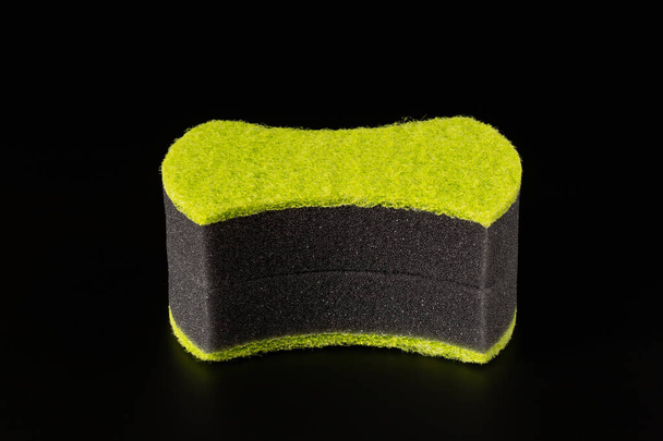 Δύο μαύρα σφουγγάρια με λειαντικό φωτεινό πράσινο στρώμα για το πλύσιμο των πιάτων και άλλες οικιακές ή οικιακές ανάγκες. Απομονωμένη σε μαύρο φόντο. Κοντινό πλάνο - Φωτογραφία, εικόνα