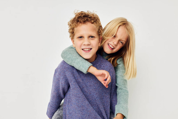 Boy and girl in multi-colored sweaters posing for fun light background - Фото, зображення