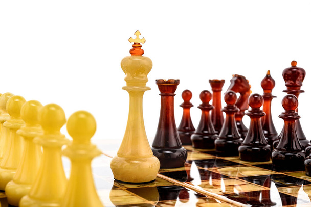 Natuurlijke barnsteen verschillende schaakstukken figuren staande op parelmoer bord in het wit. Close up game concept competitie, Classic Tournament van confrontatie. - Foto, afbeelding