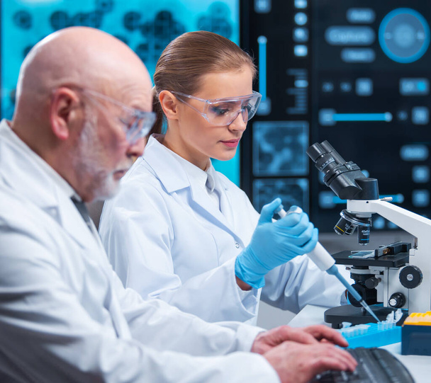 Professor and doctor work in a modern scientific laboratory using equipment and computertechnologies. Group of scientists make research and develop new vaccines. Science and healthcare concept. - 写真・画像