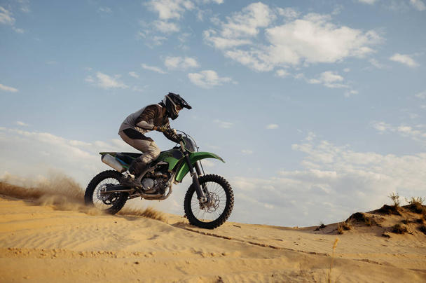 Professionele motorcross rijder glijden van zand heuvel - Foto, afbeelding