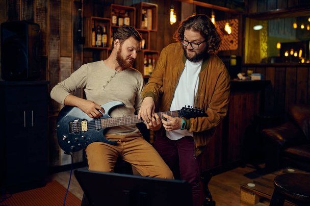 音楽家は男性学生にギターを教える - 写真・画像