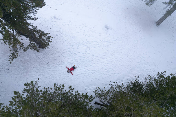 Drone aerial of woman wearing warm clothing lie down at snow in winter. Troodos cyprus - Photo, Image