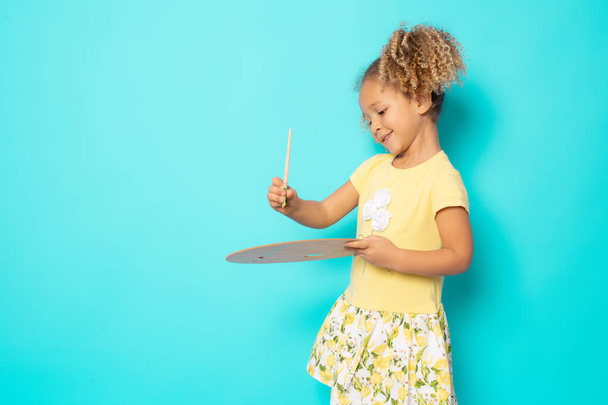 Pretty little girl painter with a brush and palette isolated over green background. - Foto, Bild