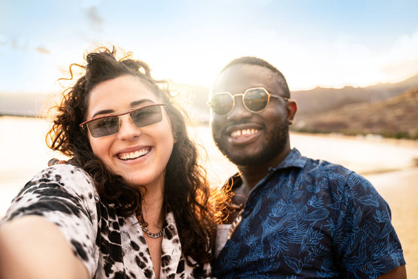 Mnohočetný šťastný pár, mladí přátelé se smějí, užívají si selfie, společně se baví na pláži. Multietnický koncept přátelství. Líbánky. Léto. Cestovatel. Emoce skutečných lidí - Fotografie, Obrázek