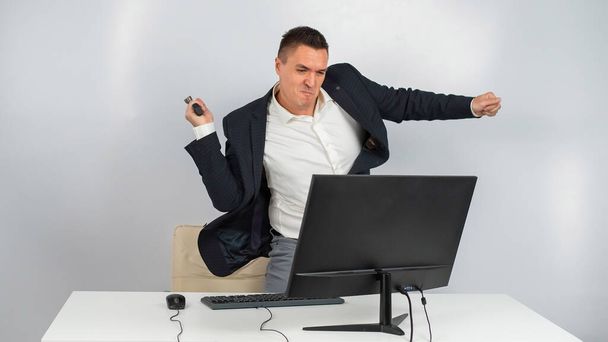 The man gets angry and smashes the monitor with a hammer. An office worker in a rage breaks the computer.  - Foto, Imagen