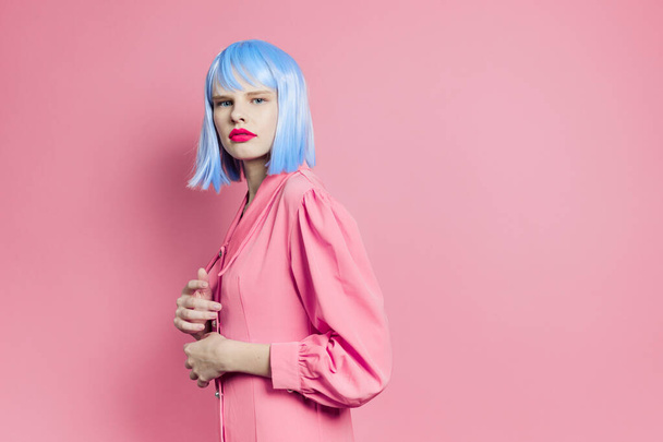 fashionable woman wears a blue wig makeup pink background - Photo, Image