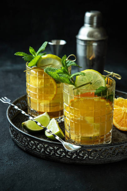 Refreshing drink with lime, orange, lemon  and  mint  leaves on dark concrete  background, selective focus with shallow depth of field - Photo, image