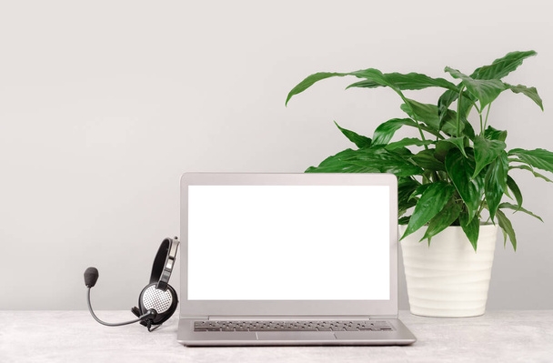 Front view of plain workspace with mockup laptop screen and headset headphones. Call center, customer support, Working from home - Фото, изображение