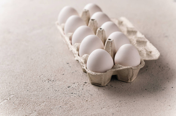 Huevos blancos de pollo en una sartén sobre un fondo claro, espacio vacío para el texto, luz lateral trasera - Foto, imagen