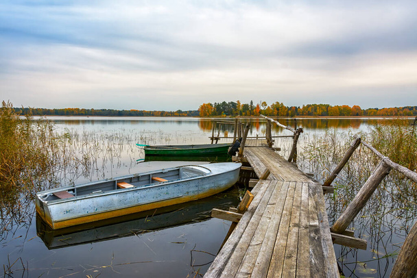 An old wooden pier on the shores of Lake Vuoksa with boats tied to it.  - Zdjęcie, obraz