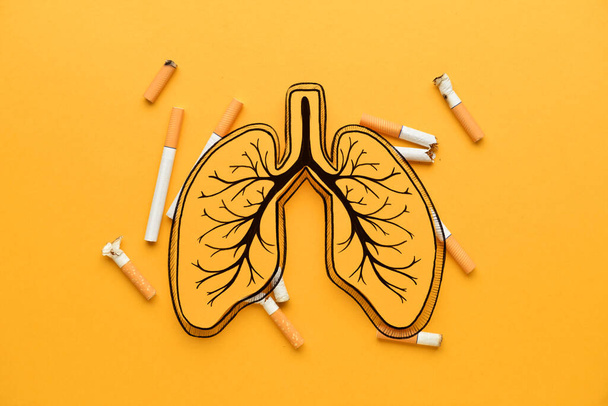 Papierowe płuca z papierosami na pomarańczowym tle - Zdjęcie, obraz