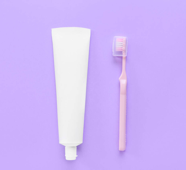 Tube met tandpasta en penseel op paarse achtergrond - Foto, afbeelding