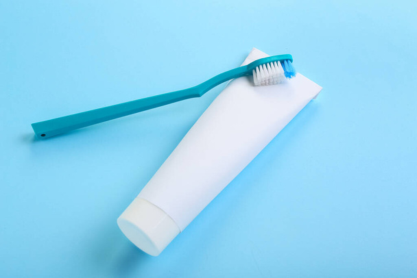 Tube met tandpasta en penseel op blauwe achtergrond - Foto, afbeelding